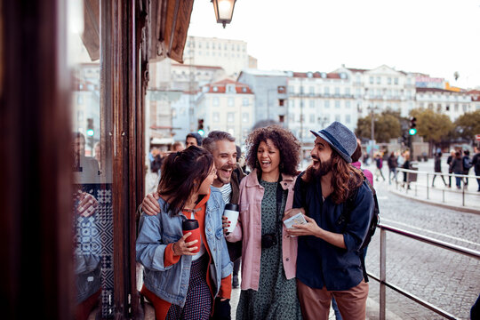 Happy friends walking and laughing on european city street