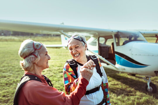 Two senior women high-fiving after skydiving at airfield