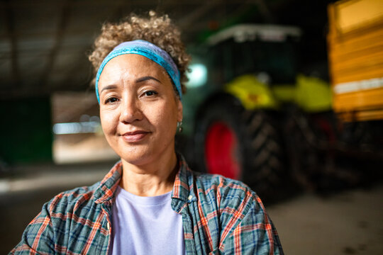 Confident woman farmer with tractor in barn