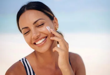 Beachside skincare moment featuring a joyful woman applying face cream or sunscreen with her eyes closed in blissful contentment © paultarasenko