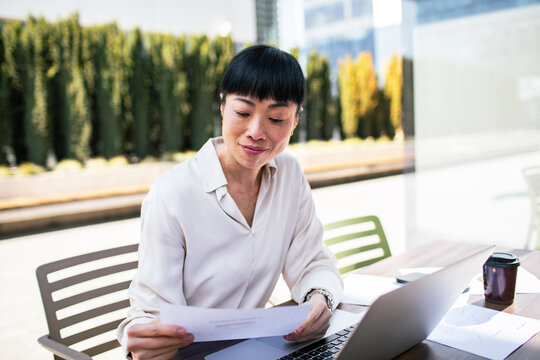 Professional woman reviewing documents on outdoor office terrace