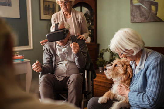 Senior man in wheelchair using vr at home with dog