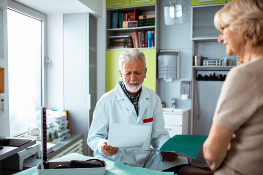 Senior doctor reviewing test results with elderly patient in clinic