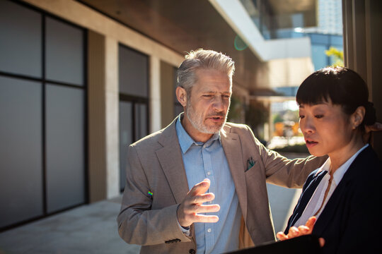 Two business professionals discussing work outside office building