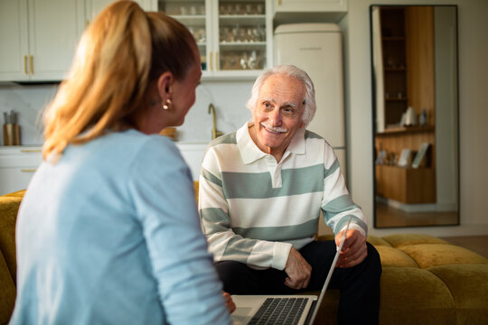 Senior man receives laptop help from woman at home