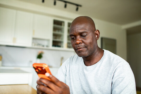 Mature man using smartphone in home kitchen