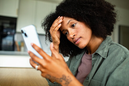 Worried young woman checking phone at home
