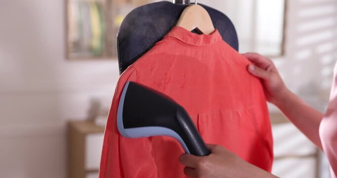 Woman steaming shirt with upright steamer at home, closeup