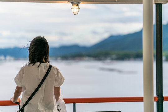 A lonely asian woman standing at side of a ship
