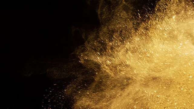 Overlay video transition, Golden powder explosion burst isolated on a solid black background creating a dynamic spray of glittering particles.