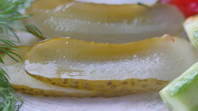 Macro view of pickled cucumber slices with fresh dill and vegetable garnish in motion