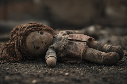 A soiled cloth doll lying on the ground, showing signs of wear.
