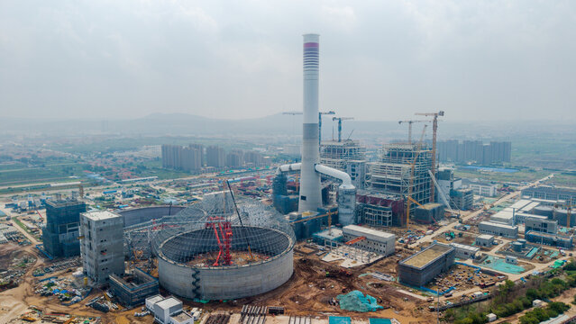 Construction Site of Industrial Facility with Chimney and Cranes