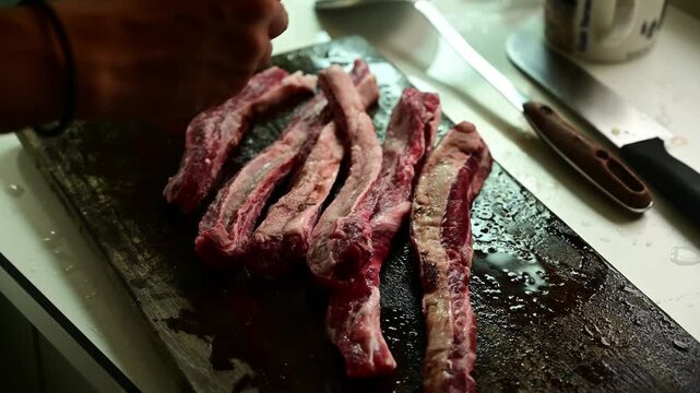 Seasoning Fresh Beef Strips with Salt on Wooden Cutting Board Before Cooking