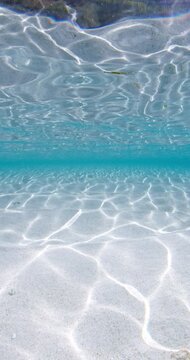 Crystal blue ocean underwater and sandy sea bottom, vertical screen