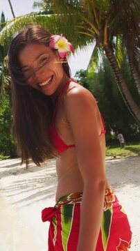 Bikini travel woman walking on beach smiling and laughing at camera, Bora Bora. Happy joyful girl on holidays wearing pareo in Tahiti, French Polynesia. Vertical video of real woman without makeup