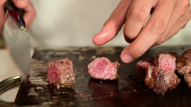 Cutting Seared Beef Strips into Cubes on Wooden Cutting Board for Cooking