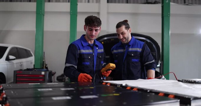 Professional EV technicians performing high-voltage battery diagnostics and electrical testing in a modern electric vehicle service workshop.