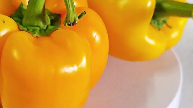 Close-up of fresh yellow bell pepper with green stem.