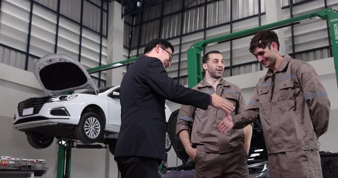 Professional EV service manager shaking hands with a skilled technician after a successful electric vehicle maintenance project in a modern automotive workshop.