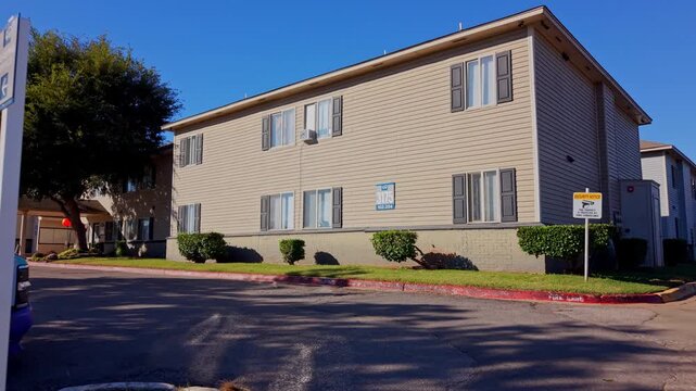 Daytime exterior shot of a multifamily housing complex with a parked truck and visible signage.