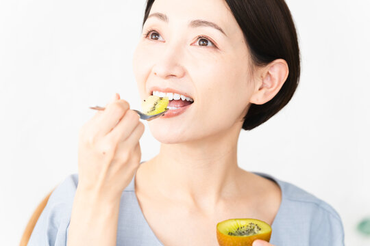キウイフルーツを食べる女性　食べ物イメージ