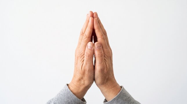 Close-up of senior hands clasped in prayer against a white background