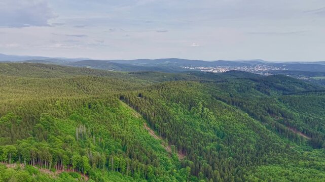 Aerial view of a lush green valley no visible action static scene, in outdoor landscape with rolling hills and dense vegetation, with hills, vegetation, with green, blue accents, nearby objects.