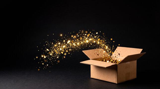Cardboard box overflowing with golden glitter and stars exploding outwards on a dark background