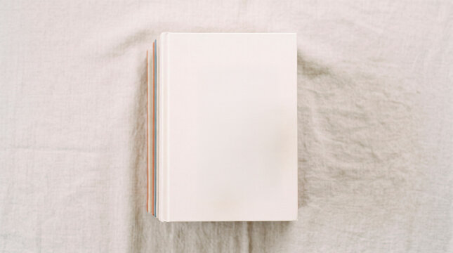 Stack of blank notebooks with pastel colored spines resting on a textured fabric surface