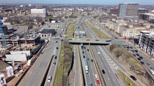 Daytime drone view flying forward over Interstate 40 in The Gulch, Nashville, Tennessee, reveals busy multilane highways, nearby construction, and city skyline