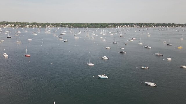 Panning Aerial shot of Salem, Massachusetts with views of boats and yachts in the harbor on a warm summer day at sunset.