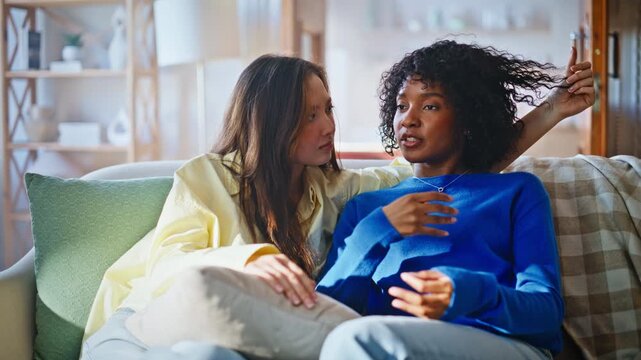 Multiethnic friends talking home sofa. Woman comforting upset worried friend.