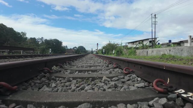 Low-Angle View of Railway Tracks Leading Through a Rural Village