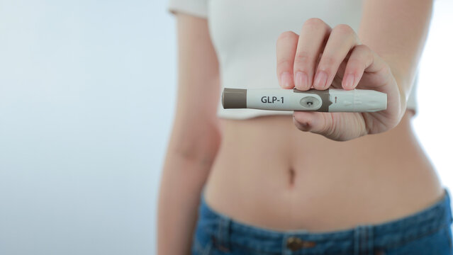 Confident woman holds modern medical injection pen device near slim belly showing successful hopeful weight loss treatment concept