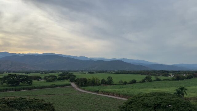 4K Panning Shot Left to Right of Colombian Sugarcane Fields Revealing Andes Mountains at Golden Hour Sunset in Valle