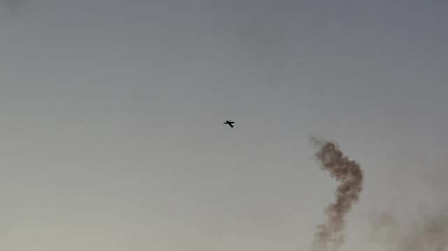 Airplane performing aerobatic maneuvers with smoke trail against sky