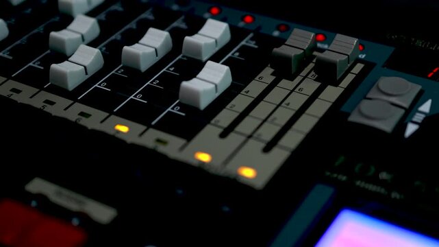 A wide close-up of a professional studio mixing console showing rows of faders, buttons, and controls in a broadcast setting.