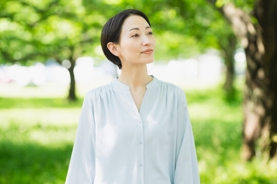並木で見上げている若い女性　ライフスタイルイメージ