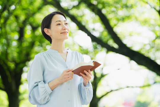 屋外で読書をする若い女性　ライフスタイルイメージ