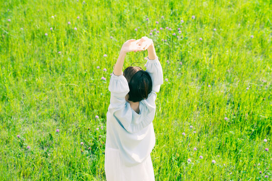 草原でストレッチをする若い女性　ライフスタイルイメージ