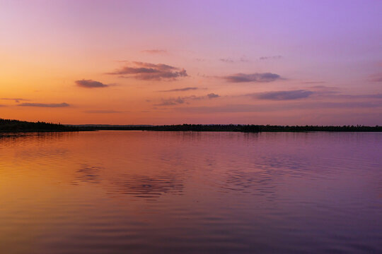 Pink purple sunset over Big Chebachye lake. Vivid gradient sky and ripples on calm water. Scenic background with symmetry reflection evening sky. Burabay National Nature Park Travel destination.