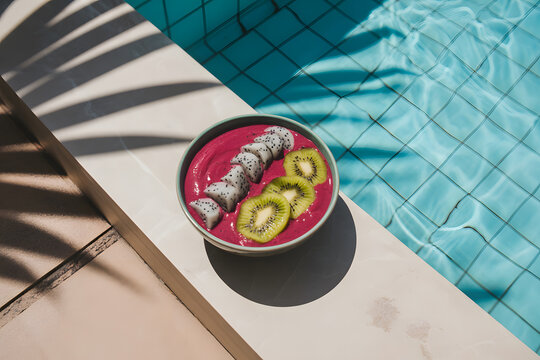 Healthy smoothie bowl with dragon fruit and kiwi served poolside for a refreshing summer breakfast vibrant and nutritious meal.
