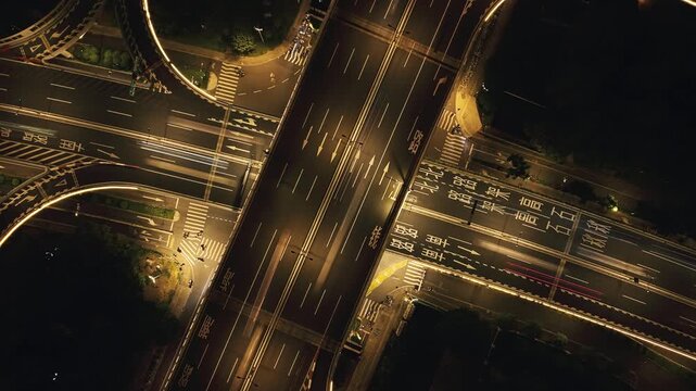 Aerial top down view captures a busy Hangzhou highway interchange at night with glowing lights and towering apartments