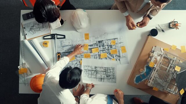 Top down view of skilled engineer team compare between blueprint and house plan. Aerial view of group of architect or designer discussing and point note to brainstorm about blueprint. Alimentation.