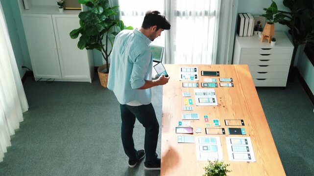 Top view of smart businessman holding tablet while looking at UX or UI design document at meeting table while analyzing data.Skilled manager choose idea or designing prototype or program. Convocation.