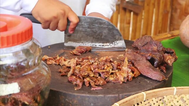 Close up chef hands slicing dried cured beef meat on wooden chopping board 4K