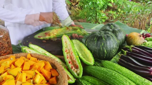Chef deseeded fresh bitter gourd with spoon on wooden chopping board 4K