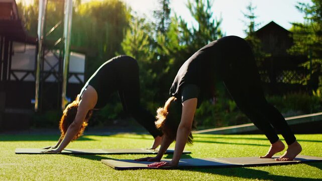 Elderly women practicing slow motion Pilates outdoors on yoga mats, focusing on gentle strength, balance, and flexibility exercises together in peaceful sunlight