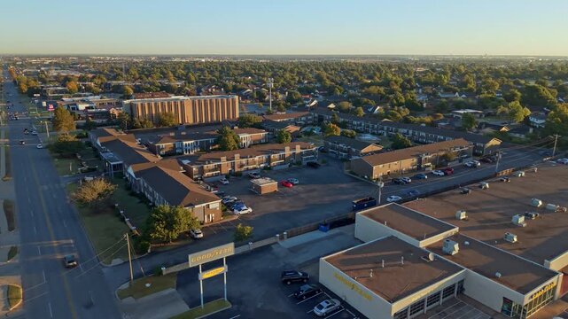 Afternoon aerial view of a neighborhood featuring multifamily housing complexes, commercial buildings, and tree-lined streets.